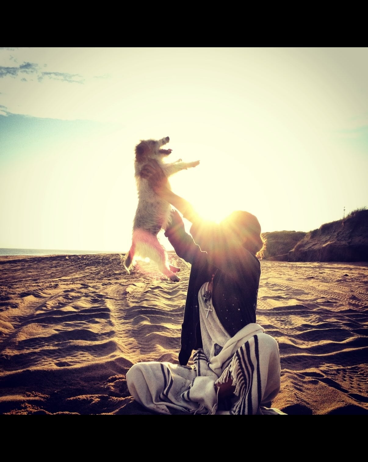 Candelaria Tinelli eleva a su perra Linda en una playa iluminada por el sol tras el fallecimiento de la mascota.