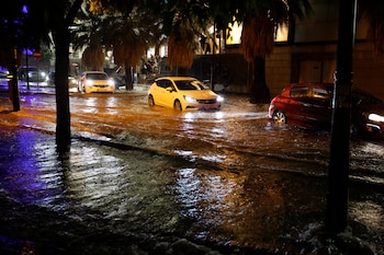Coches circulan por una calle inundada tras las fuertes lluvias caídas en Valencia, este miércoles. (Ana Escobar/EFE)