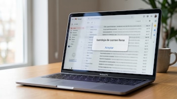 Primer plano de una laptop MacBook Pro plateada sobre un escritorio de madera, mostrando la interfaz de Gmail con un mensaje emergente: "bandeja de correo llena".