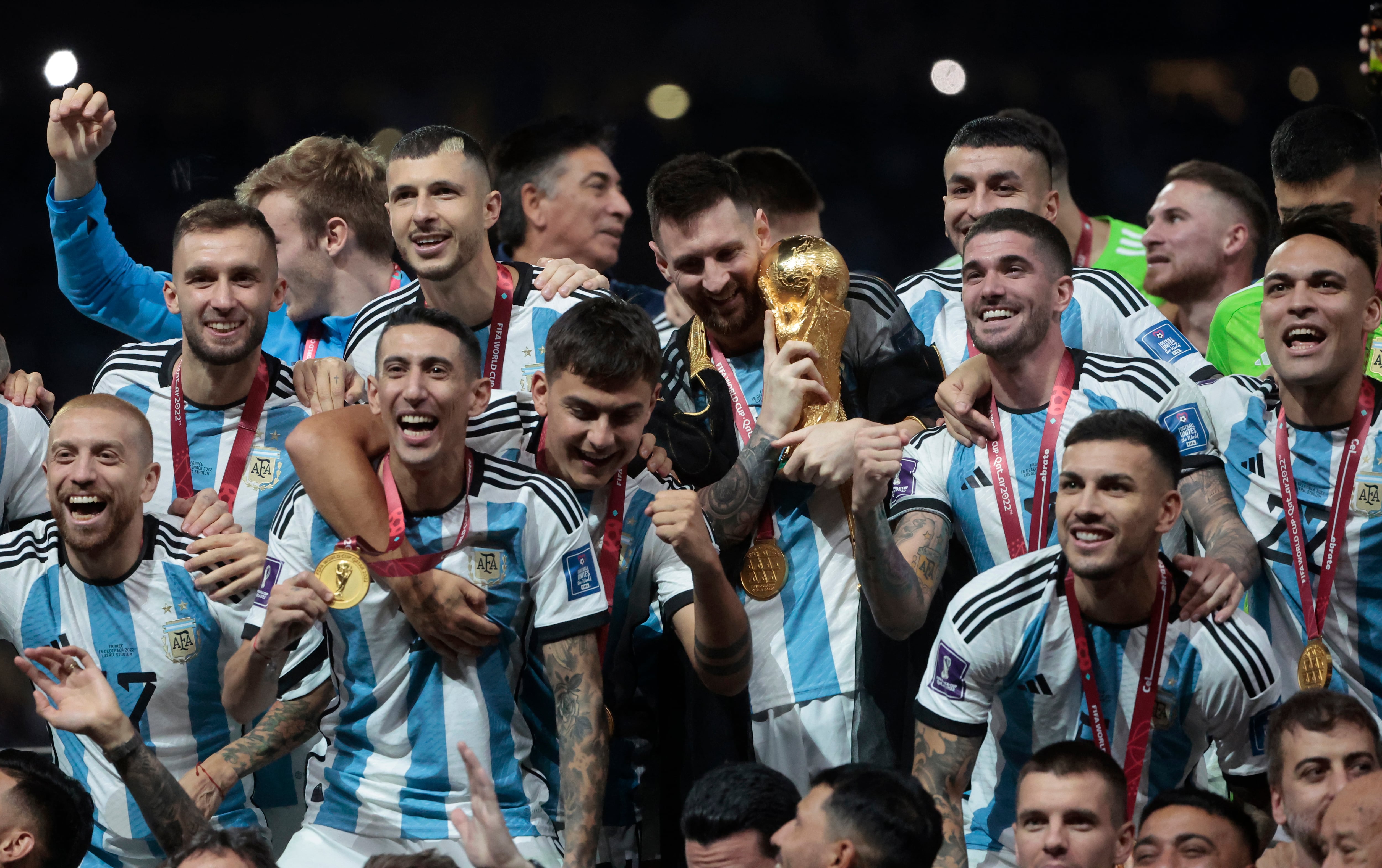 Messi abrazado a la Copa del Mundo, rodeado de sus compañeros en Qatar. La Selección iniciará la defensa del título (Foto EFE)