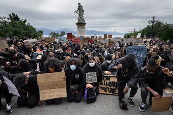 People kneel down as they take part in a rally on June 7, 2020 in Lausanne against racism and police brutality in the wake of the death of George Floyd and in memory of 40 year old Nigerian Mike Ben Peter who died in similar circumstances after a police control in Lausanne two years ago. (Photo by Fabrice COFFRINI / AFP)