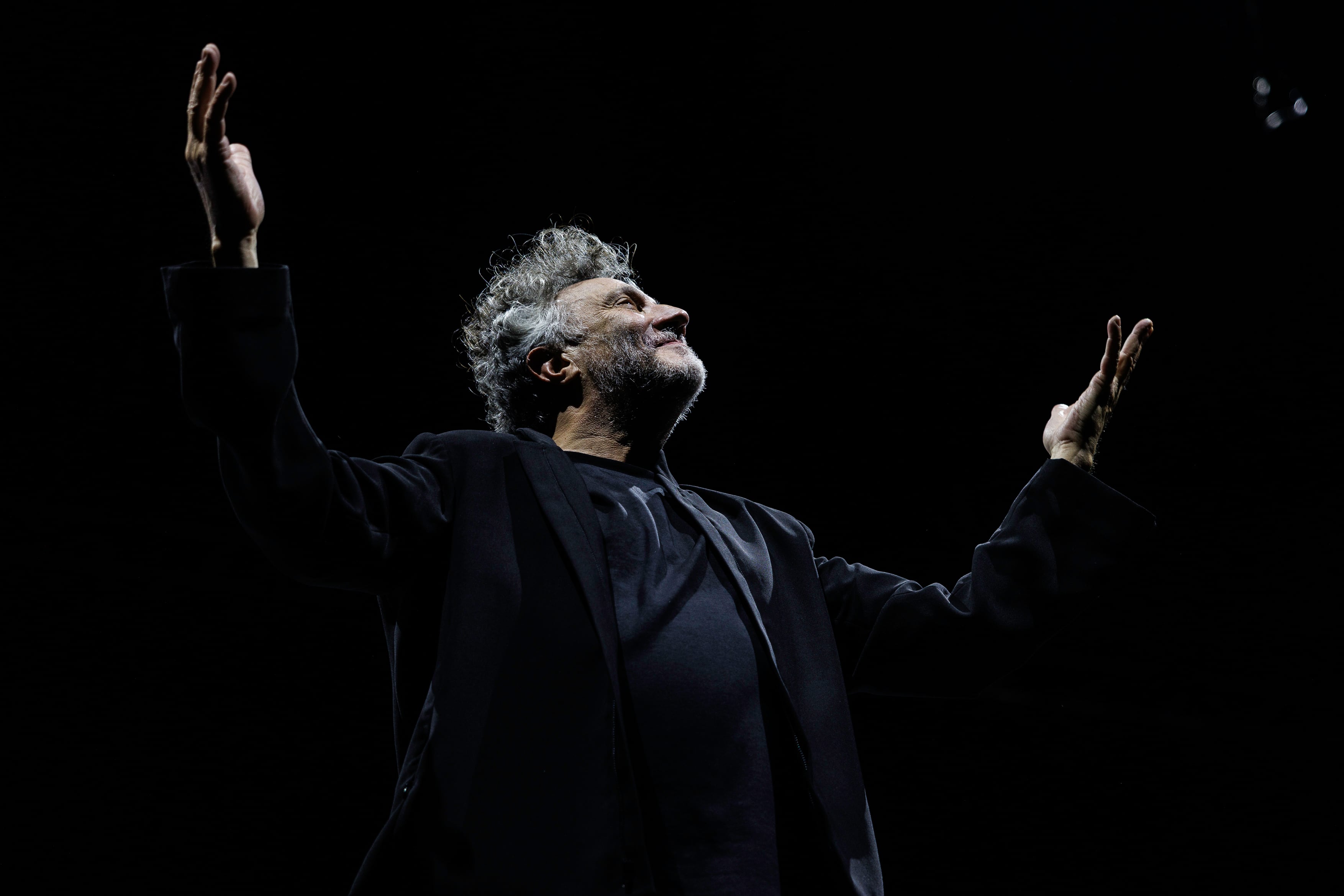 El reconocido artista Fito Páez, con los brazos en alto y la mirada hacia arriba, irradia pasión en su concierto. (Guido Adler)