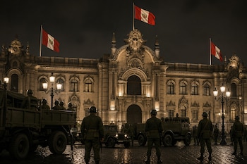 Soldados de espalda y camiones militares frente al edificio iluminado del Palacio de Gobierno con tres banderas peruanas.