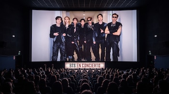 Pantalla de cine que proyecta a los integrantes de BTS frente a un público sentado en las butacas de la sala.