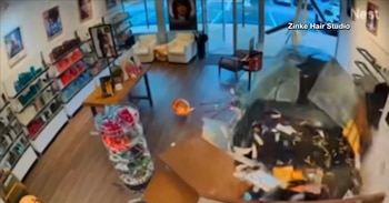 Vista desde una cámara de seguridad del interior de una peluquería con cristales rotos y muebles destrozados tras el choque de un vehículo
