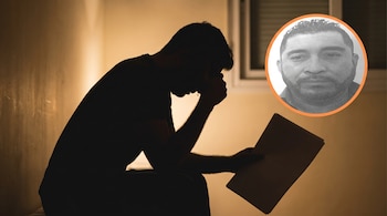 Silueta oscura de un hombre sentado, con la cabeza gacha y una lágrima, sosteniendo documentos. En la esquina superior derecha, un retrato en blanco y negro de un hombre con barba.