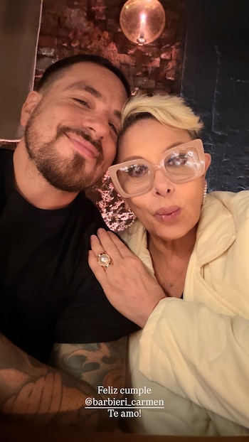 Selfie de Fede Bal, sonriendo, junto a Carmen Barbieri con gafas grandes y chaqueta clara, posando cariñosamente en un ambiente oscuro con luz cálida