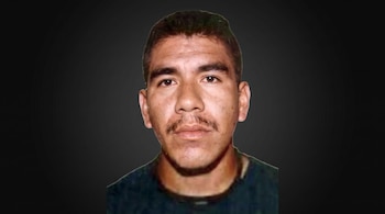 Fotografía frontal de un hombre de piel morena con cabello oscuro y bigote, vestido con una camisa oscura, sobre un fondo gris degradado.