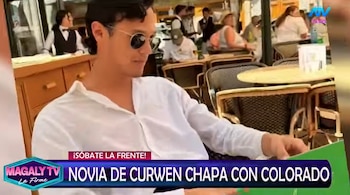 Hombre joven con camisa blanca y gafas de sol, sentado en una mesa de un restaurante al aire libre con otros comensales y logotipos televisivos