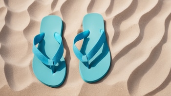 Imagen de ojotas sobre la arena de una playa, evocando descanso y turismo en un fin de semana largo. Un par de chanclas descansan en la costa. (Imagen ilustrativa Infobae)