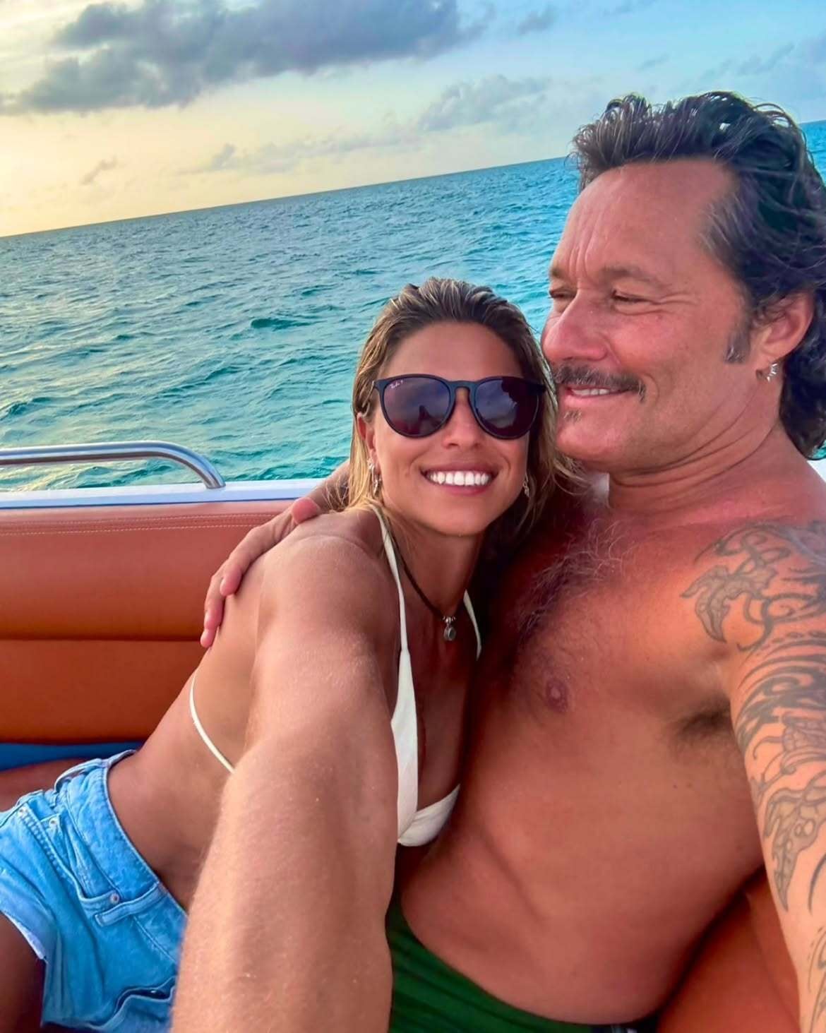 Diego Torres y Martina Díaz Radonic, a bordo de una lancha durante sus vacaciones en el Caribe. Él la rodea con el brazo mientras el cielo vira a tonos anaranjados sobre el mar