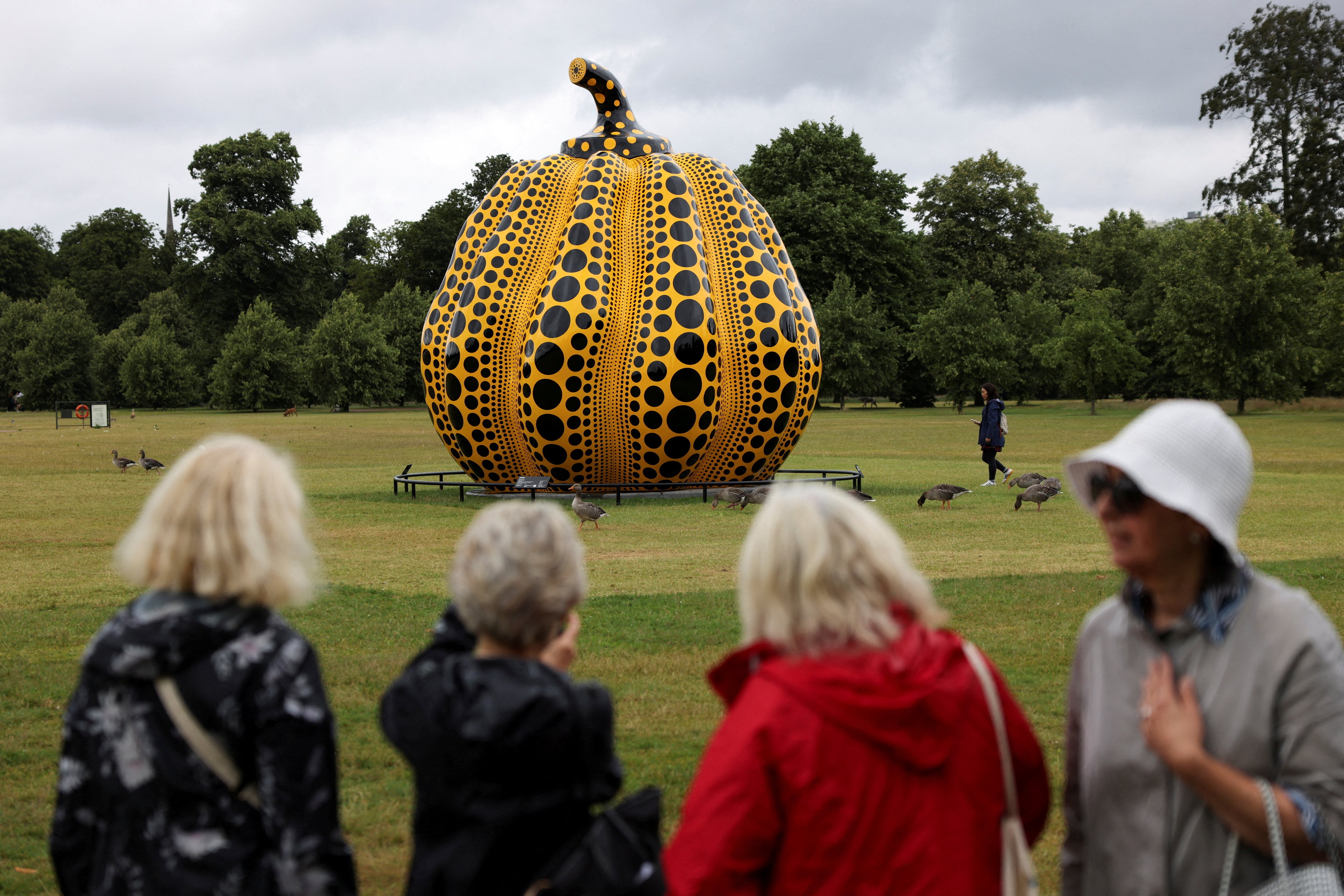 Personas observan la escultura «Pumpkin» de la artista japonesa Yayoi Kusama en los jardines del Palacio de Kensington, en Londres (REUTERS/Hollie Adams/Archivo)