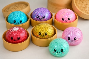 Esferas de colores con brillo y caras caricaturescas junto a recipientes de bambú sobre una mesa.