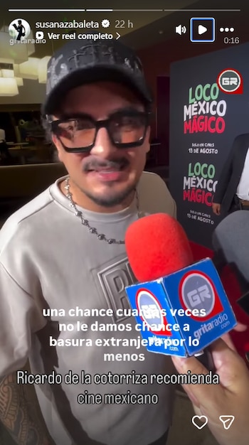 Primer plano de un hombre con gorra negra, gafas y bigote, hablando en un micrófono rojo con logo GR, frente a un cartel de 'Loco México Mágico'