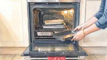 Ilustración en acuarela de unas manos que sostienen un molde frente a un horno abierto con varias bandejas.