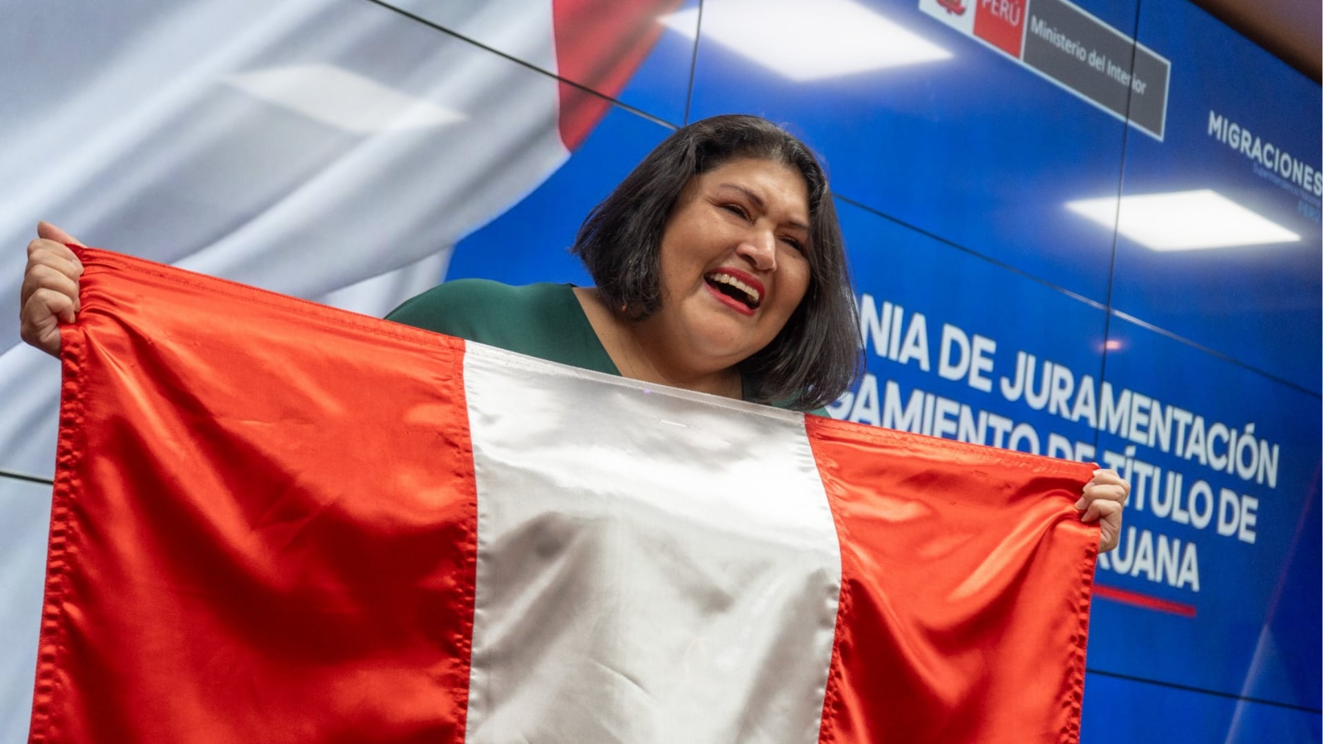 Una mujer sostiene la bandera del Perú durante la ceremonia de juramentación organizada por la Superintendencia Nacional de Migraciones en Jesús María. (Migraciones)