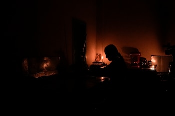 Mónica Valiente espera que lleguen clientes en su panadería, iluminada con una vela, durante un apagón eléctrico por racionamiento, el martes 15 de octubre de 2024, en Quito, Ecuador. (AP Foto/Dolores Ochoa)