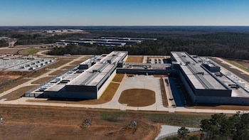 Vista aérea del complejo Stanton Springs Data Center, con grandes edificios grises, zonas de aparcamiento, y una subestación eléctrica en un paisaje rural