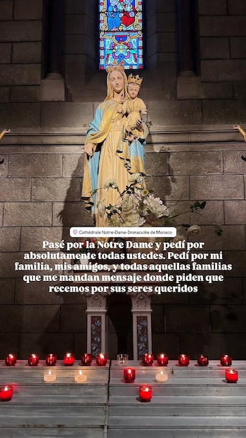 Estatua de la Virgen María y el Niño Jesús con coronas. Vitral de colores. Velas rojas y blancas encendidas en escalones. Pared de piedra