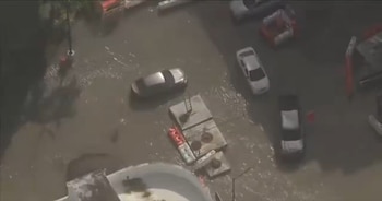 Vista aérea de una calle anegada con varios automóviles sobre el agua y bloques de concreto