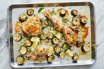 Chicken on a sheet pan with the zucchini pieces and tossed in a garlic mixture in New York on June 22, 2021. You can double this bright and tangy meal to serve a small gathering. Food Stylist: Judy Kim. (Linda Xiao/The New York Times)