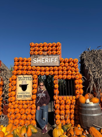 Luisana Lopilato de pie en el vano de una estructura cubierta de calabazas anaranjadas con un letrero que dice Sheriff