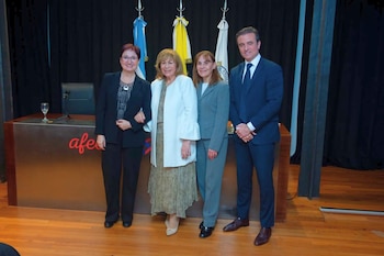 Cuatro personas en traje de negocios posando. Detrás, un podio de madera con el logo 'afe' en rojo y tres banderas colgando