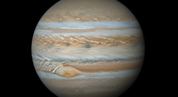 Imagen detallada del planeta Júpiter, mostrando sus icónicas bandas de nubes en tonos marrones, blancos y naranjas, y la Gran Mancha Roja visible.