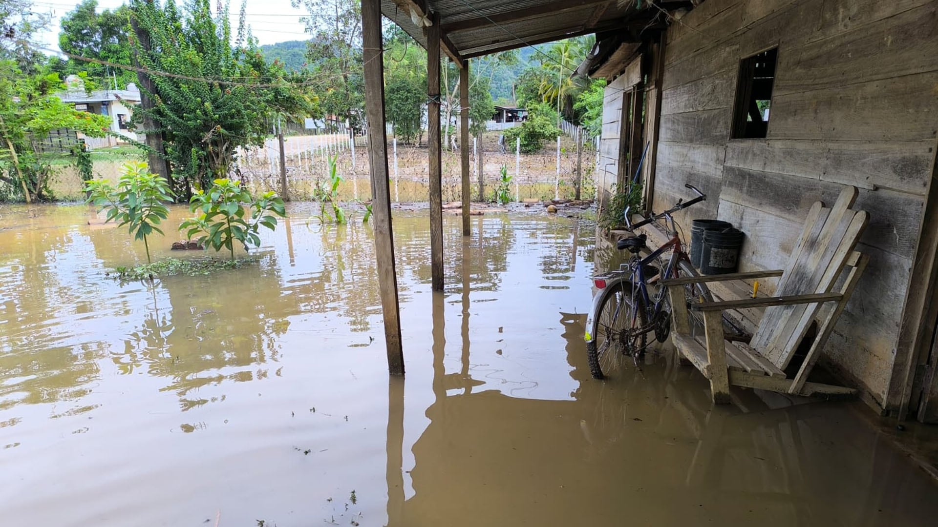 El agua de las inundaciones cubre el suelo frente a una casa de madera en Guatemala, tras las intensas lluvias registradas en las últimas horas. (SE CONRED Guatemala)