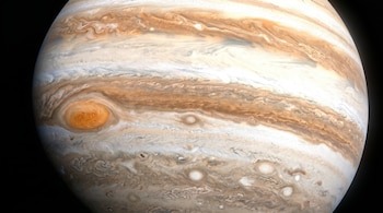 Primer plano del planeta Júpiter contra un fondo negro, con su Gran Mancha Roja y bandas de nubes arremolinadas en tonos blancos y marrones.