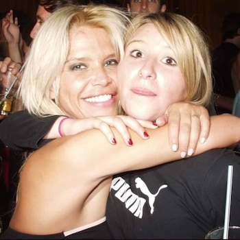 Nazarena Vélez, rubia y sonriente, abraza a su hermana Jazmín Vélez, también rubia, quien saca la lengua. Ambas aparecen en un ambiente social