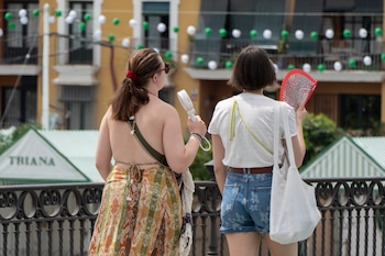 Dos personas con un abanico y un ventilador este sábado, en Sevilla. (David Arjona/EFE)