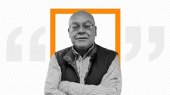 Retrato de un hombre mayor calvo con gafas, camisa a rayas y chaleco oscuro. Tiene los brazos cruzados y un marco naranja lo rodea.