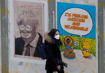Una mujer con barbijo pasa junto a un póster que se burla del primer ministro británico, Boris Johnson, en Manchester, Reino Unido. 30 marzo 2020. REUTERS/Phil Noble