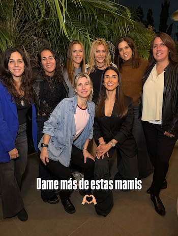 Siete mujeres posan de noche frente a plantas de hojas verdes, con el texto superpuesto Dame más de estas mamis y un emoticono de corazón