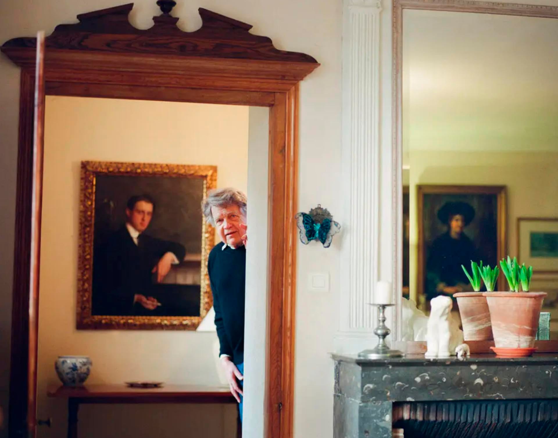 Holland en su casa, con un cuadro de su padre detrás (Clara Watt / The New York Times)