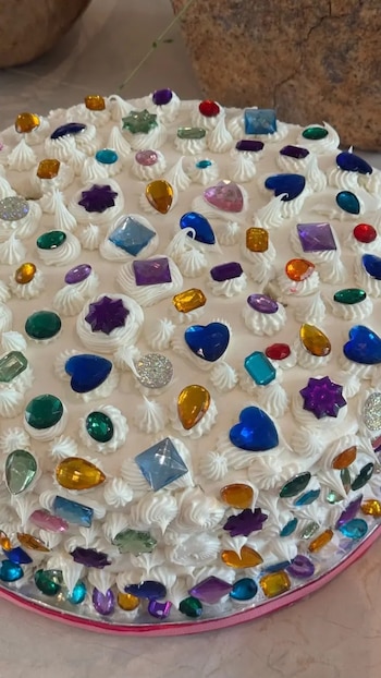 Una de las tortas presentadas era completamente blanca y estaba decorada con gemas de colores, aportando un toque de brillo y sofisticación a la mesa central