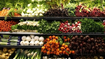 Múltiples estantes de un supermercado repletos de vegetales frescos y coloridos como zanahorias, rábanos rojos y blancos, remolachas y cebollinos