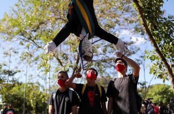 Manifestantes golpean un muñeco con