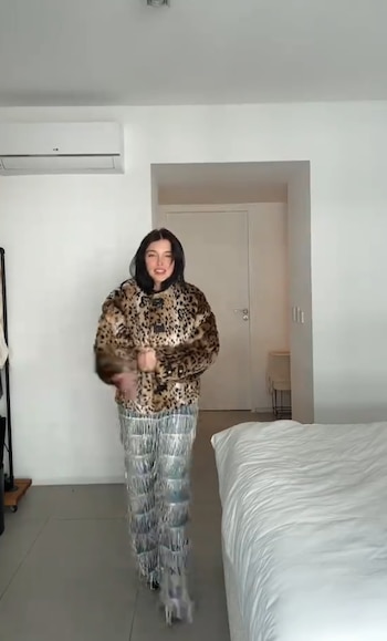 Sofía Gonet de pie en un dormitorio con una chaqueta de estampado de leopardo y un pantalón plateado de flecos