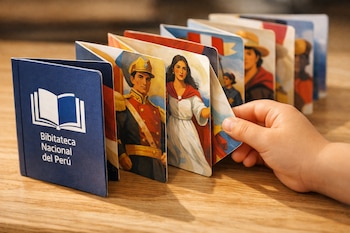 Libro leporelo desplegado sobre una mesa de madera clara. Se ven ilustraciones de figuras históricas, el logo de la Biblioteca Nacional del Perú y una mano infantil.