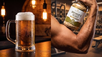 Jarra de cerveza con espuma sobre una mesa y bombillas. Un brazo musculoso sostiene un bote de levadura de cerveza con un gimnasio de fondo borroso.