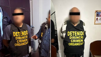 Dos hombres con el rostro cubierto llevan chalecos negros con la inscripción en letras amarillas Detenido Dirincri Crimen Organizado