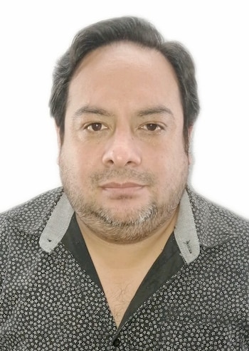 Retrato frontal de Ignacio Távara Arroyo vistiendo una camisa oscura con estampado sobre un fondo blanco