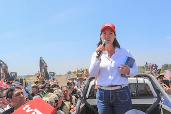 Keiko Fujimori, con gorra roja, camisa blanca y jeans azules, habla por micrófono desde una camioneta, rodeada de público y excavadoras