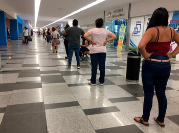 Consumidores esperan en fila para