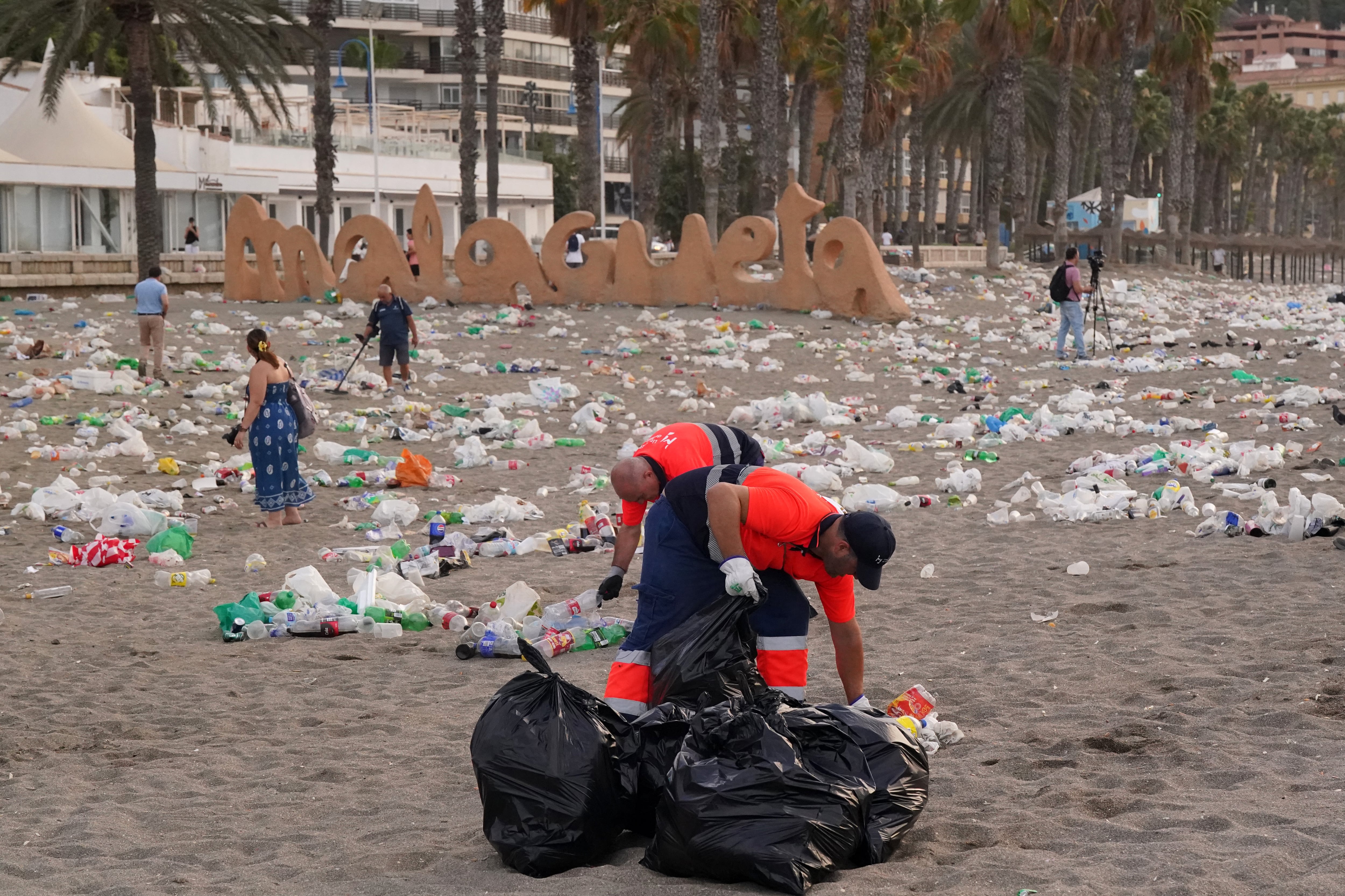 Miembros del servicio de limpieza municipal de Málaga recogen restos de basura en la playa de La Malagueta tras la celebración de la noche de San Juan, a 24 de junio de 2025. (Álex Zea / Europa Press)