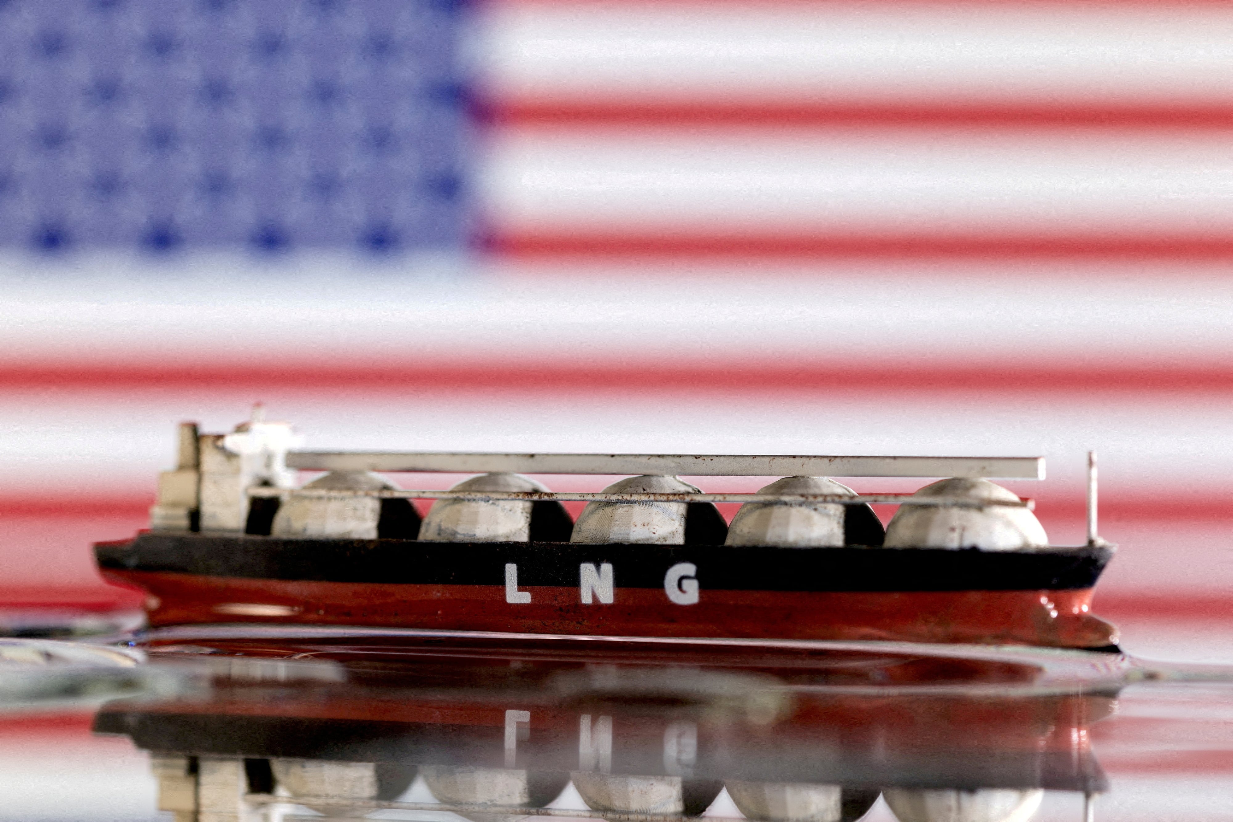 Se observa una maqueta de un buque cisterna de GNL frente a la bandera de Estados Unidos (REUTERS/Dado Ruvic/Ilustración)
