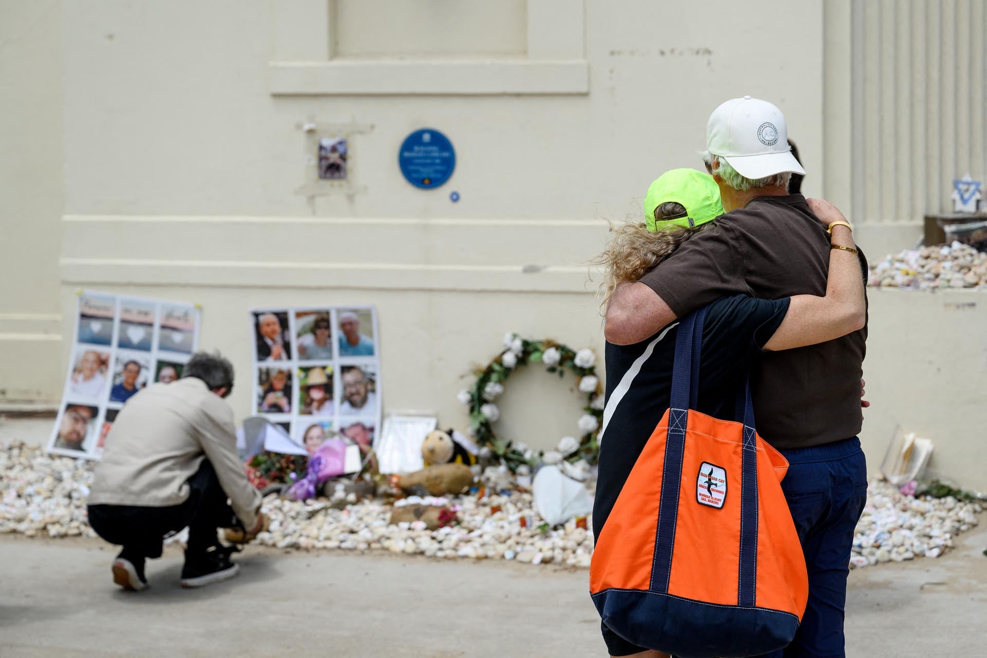 La gente se consuela mientras contempla ofrendas florales en memoria de las víctimas del tiroteo del 14 de diciembre en Bondi Beach, en el Bondi Pavilion de Sídney, el 22 de enero de 2026, como parte del día nacional de luto. (Foto de Steven Markham / AFP)