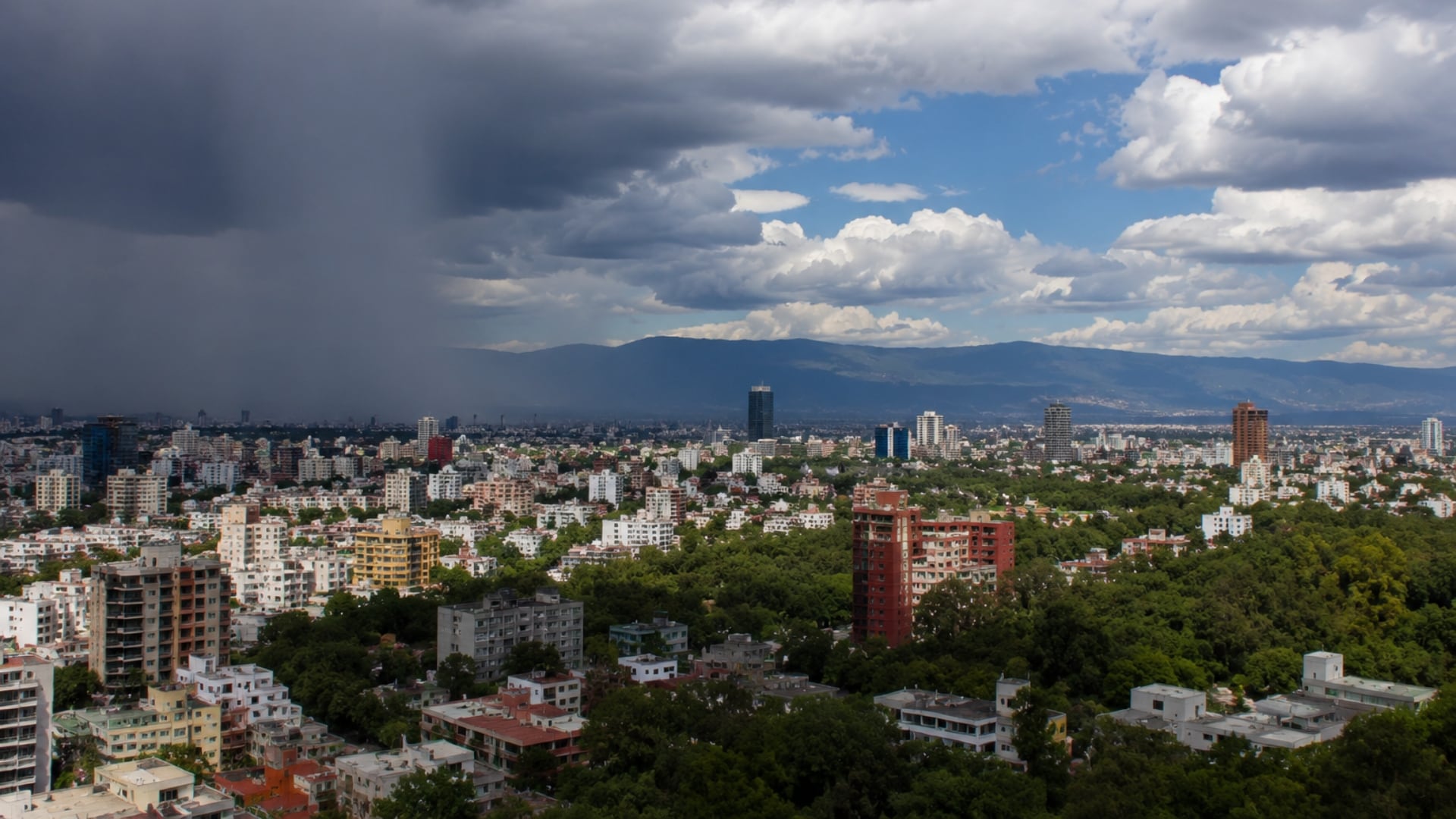 La imagen muestra un paisaje urbano de México con un cielo dividido entre nubes oscuras de tormenta en un lado y nubes blancas con cielo azul en el otro, reflejando las condiciones meteorológicas del 19 de junio de 2026. (Imagen ilustrativa IA Infobae)
